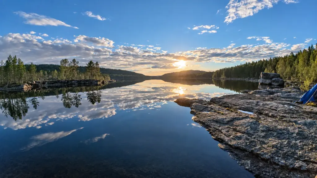 Still lake with a rocky shoreline and forest at sunrise