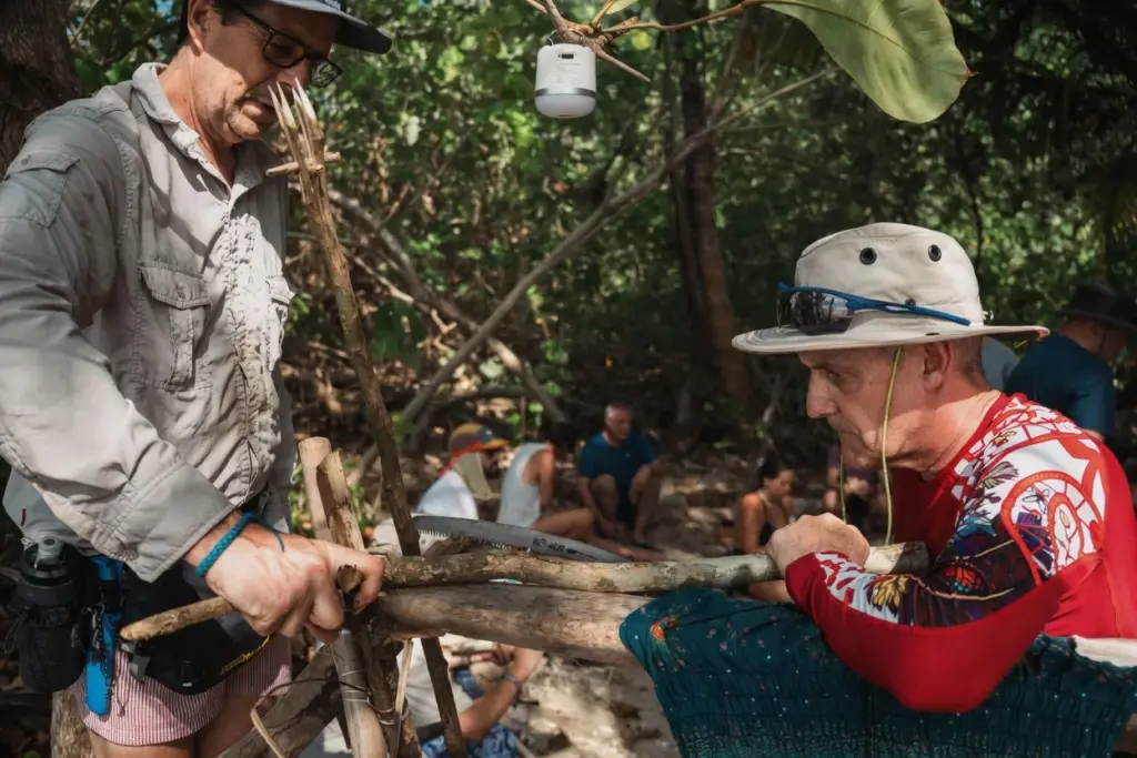 Two people sawing and preparing wood at camp
