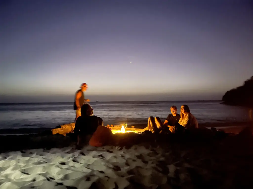 Small group around a campfire on a beach at dusk