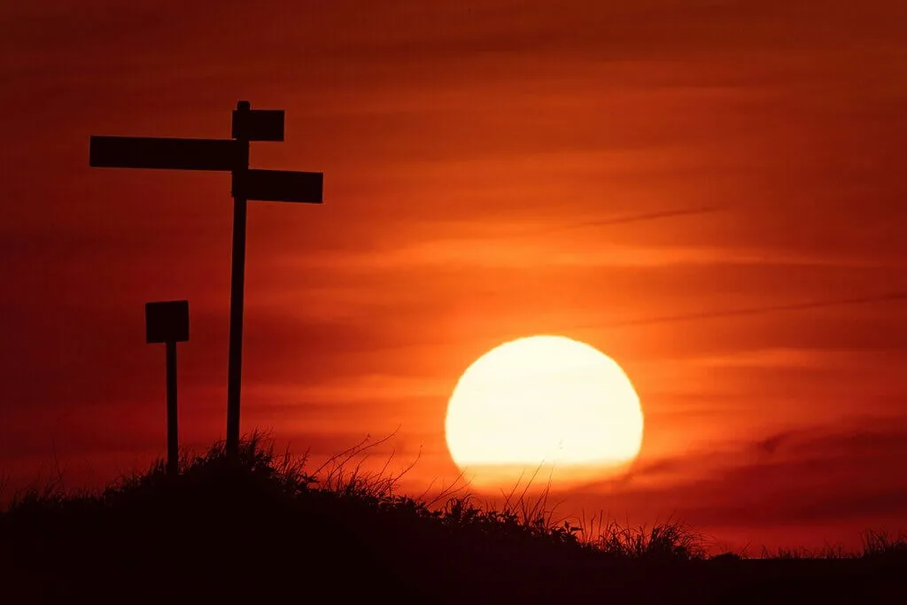 Silhouette of a signpost against a vibrant sunset, hinting at finding direction.