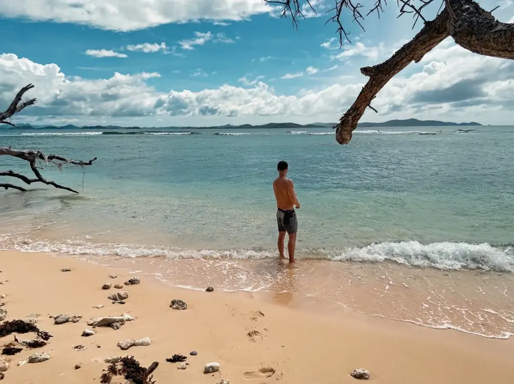 Person standing alone at the water's edge looking out to sea