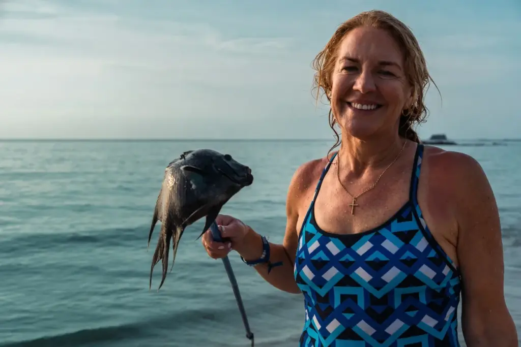 Smiling participant holding up a fish caught from the shore