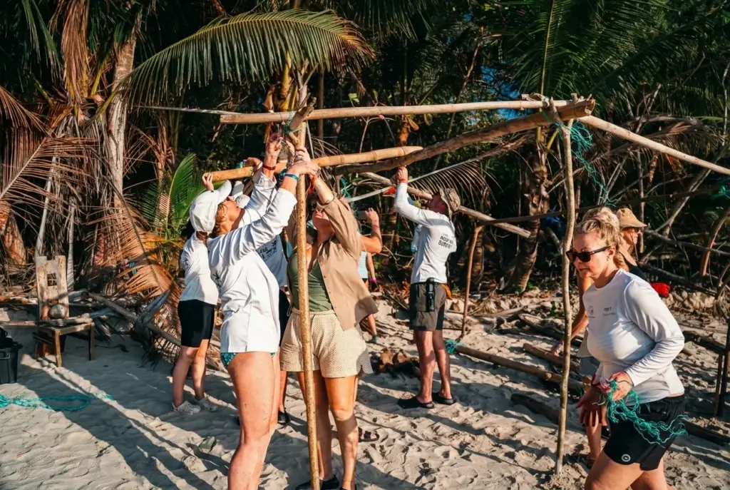 Team lashing together a shelter frame on the beach