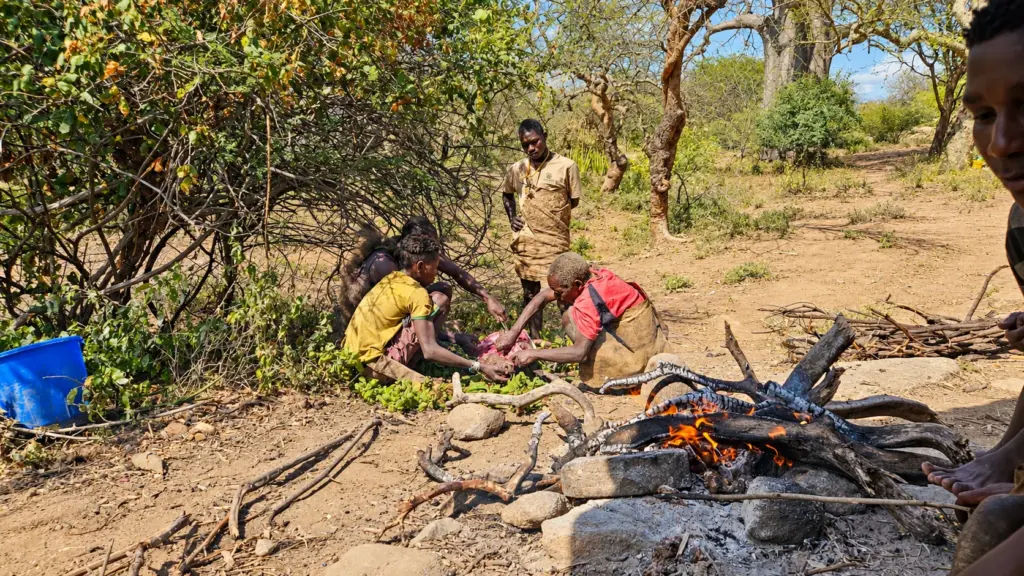 Hadza hunter-gatherers preparing food over a fire near Lake Eyasi, Tanzania