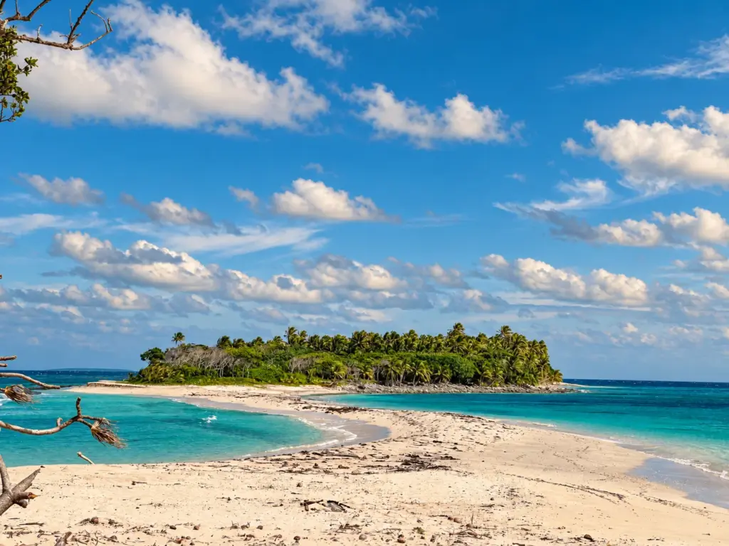 Sandbar leading to a palm-covered island in turquoise water in Tonga