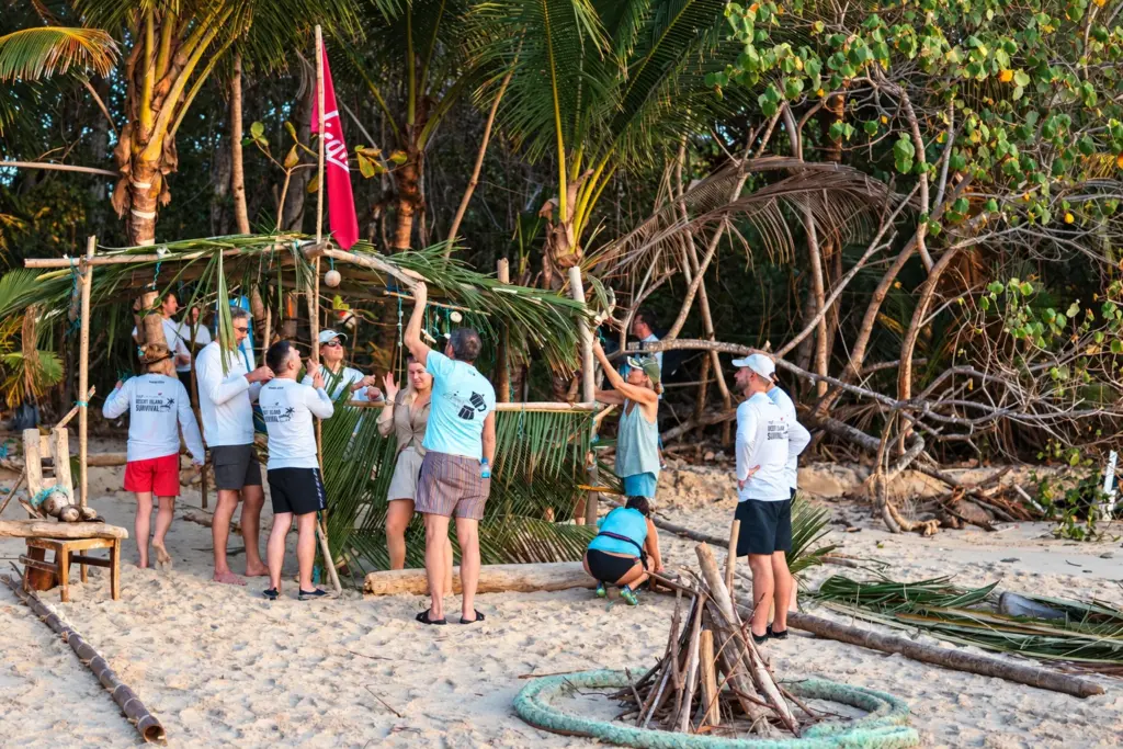 Group building a palm-roofed shelter together on the beach