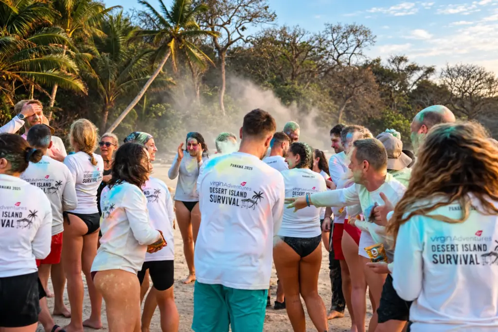 Expedition group in Desert Island Survival shirts celebrating together on the beach