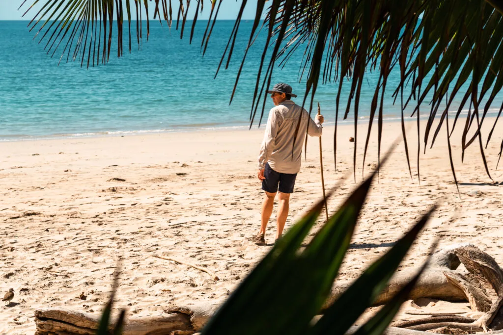 Man on beach, looking out at the ocean, enjoying a day without technology.