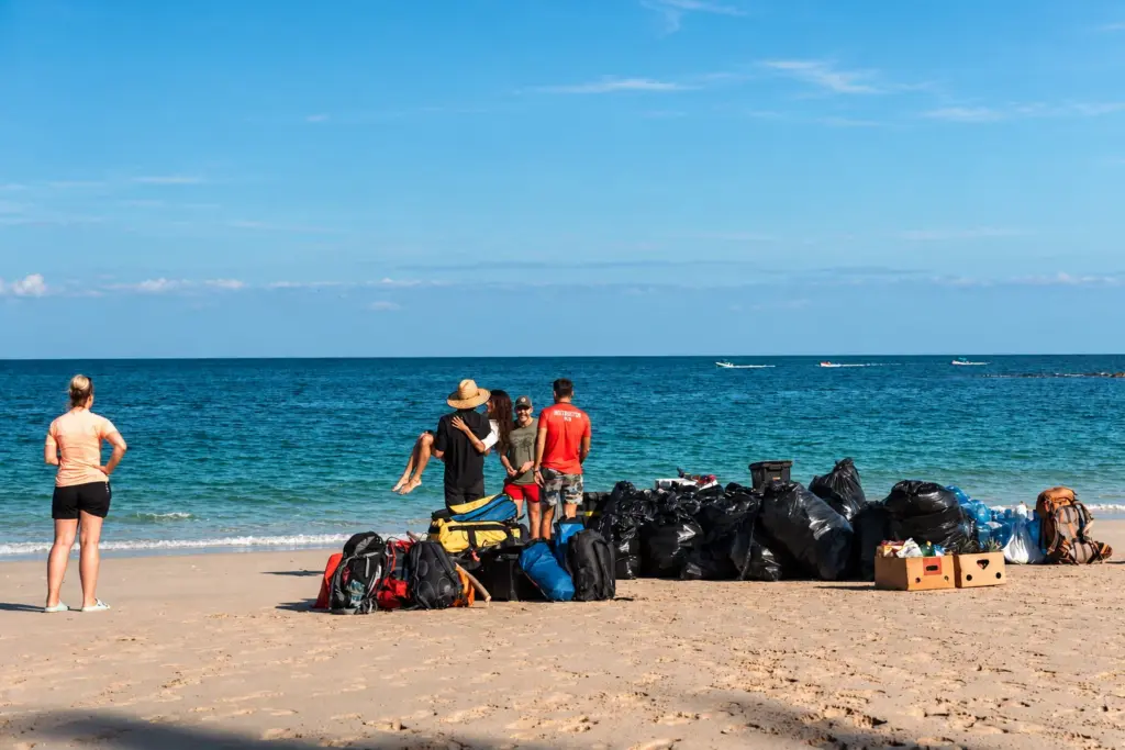 Expedition group standing beside a pile of bags and gear on arrival at the beach