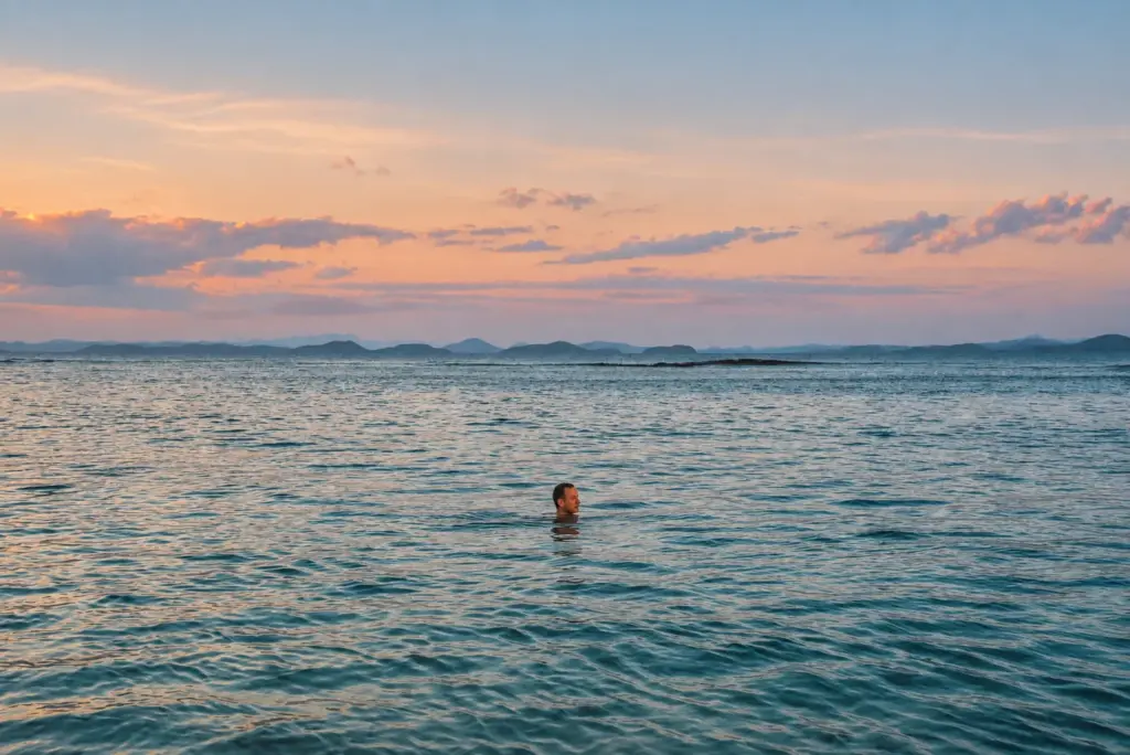 Lone swimmer in a calm, cool sea at dawn in the Philippines