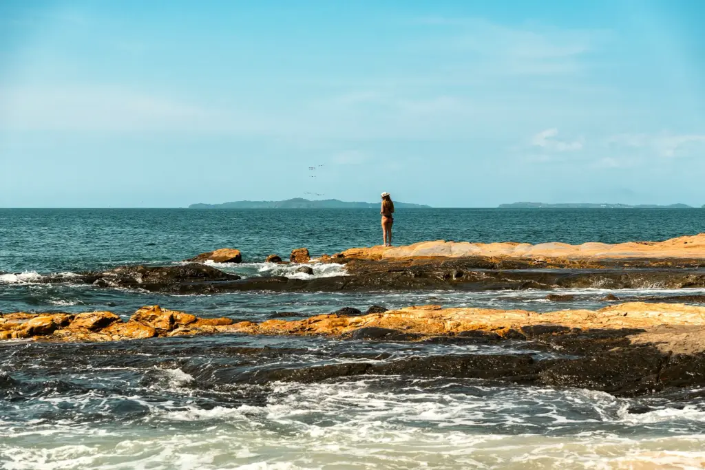 Woman standing alone on coastal rocks looking out to sea on a Panama island