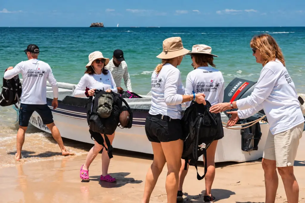 Desert Island Survival participants unloading backpacks from a boat on arrival at the island beach