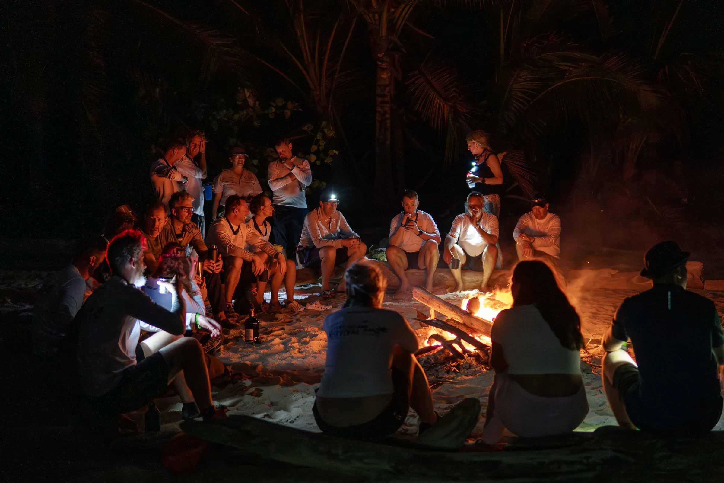 Survival skills on a desert island, group sitting around campfire at night, team building and adventure activities in an.