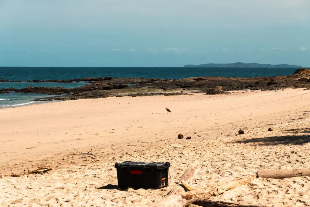 Beach with survival toolbox on a deserted island, remote island, coastal survival, desert island essentials, ocean view.