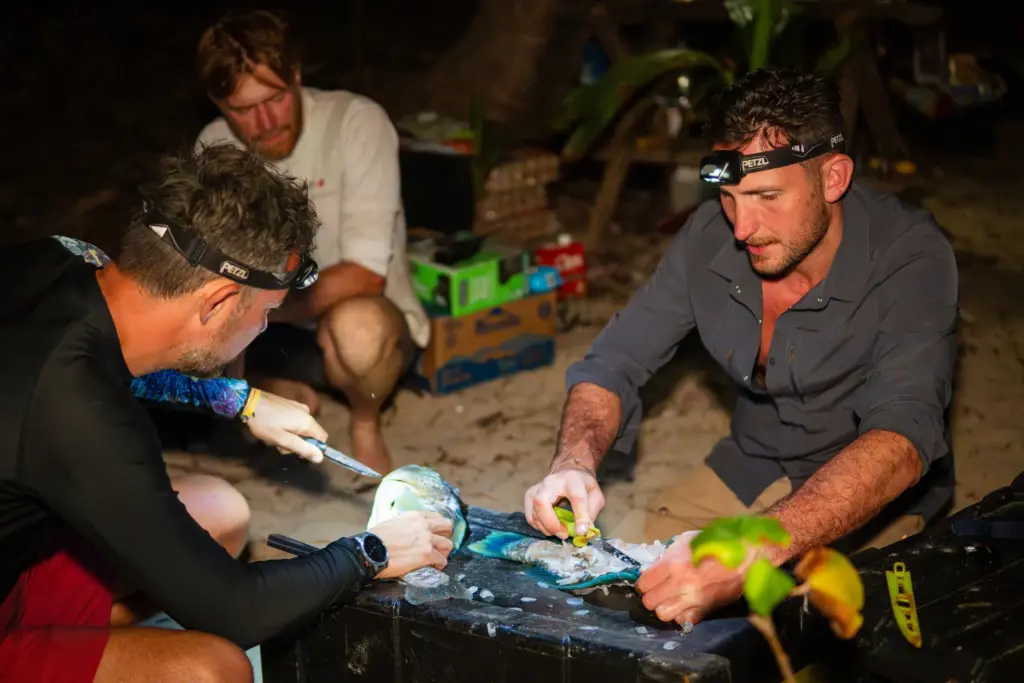 Fresh fish preparation in a survival situation on a desert island at night.