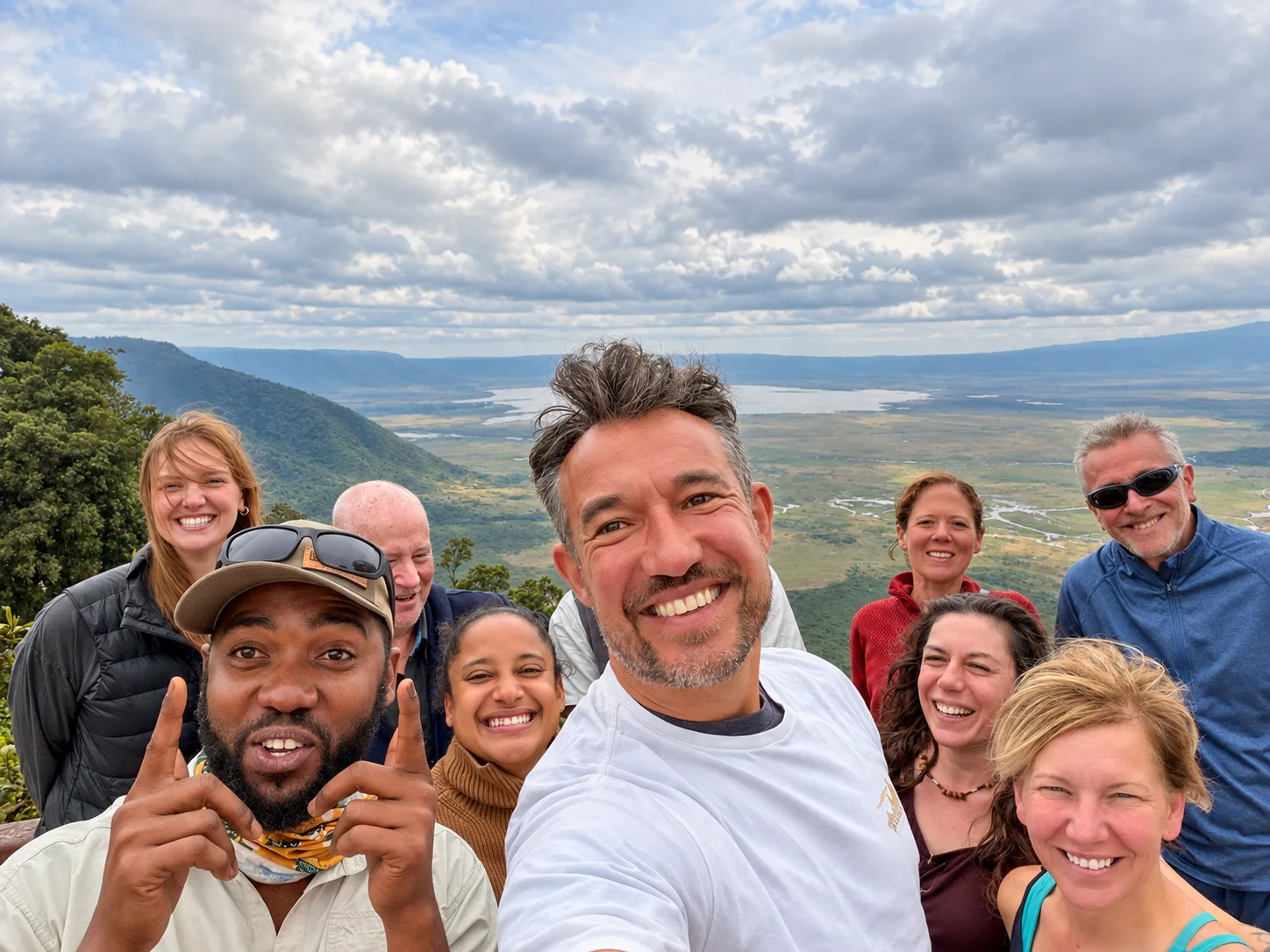 Group selfie in Tanzania with a scenic savanna and cloudy sky background