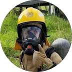Firefighter in yellow helmet and mask gives thumbs up
