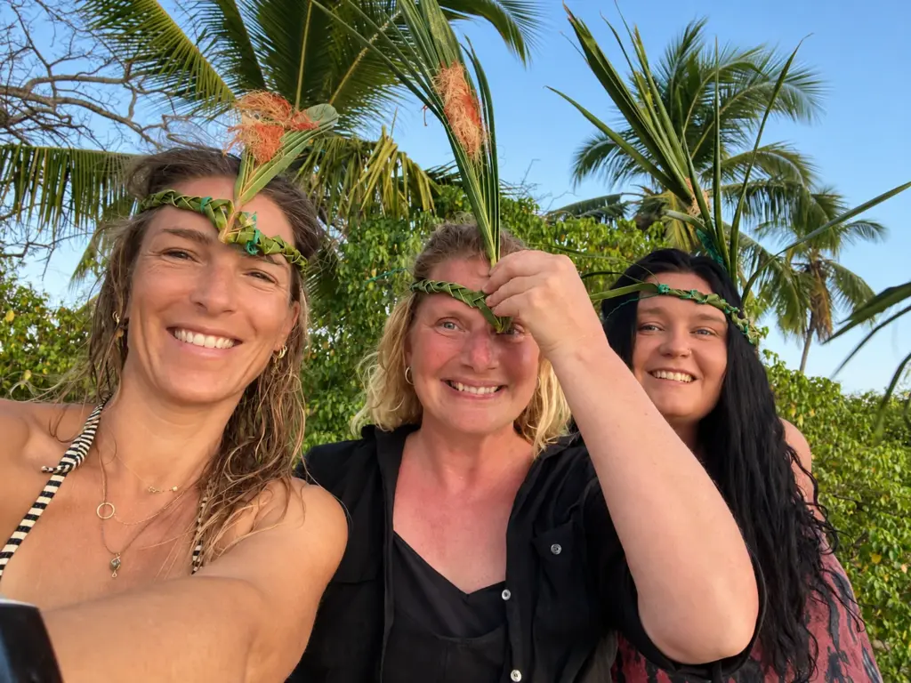 Three smiling participants share a selfie under the palms