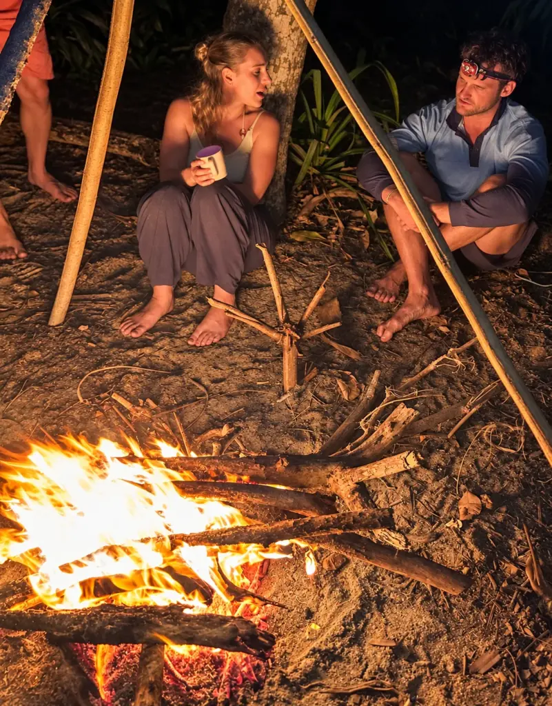 Participants relax beside a crackling campfire at night