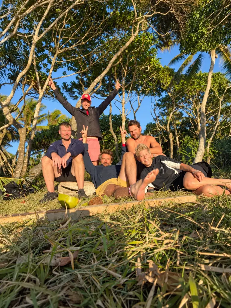 Participants celebrate together on a grassy rise under the trees