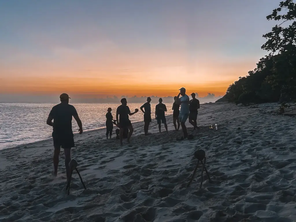 Group of people on beach at sunset, possibly on a survival expedition.