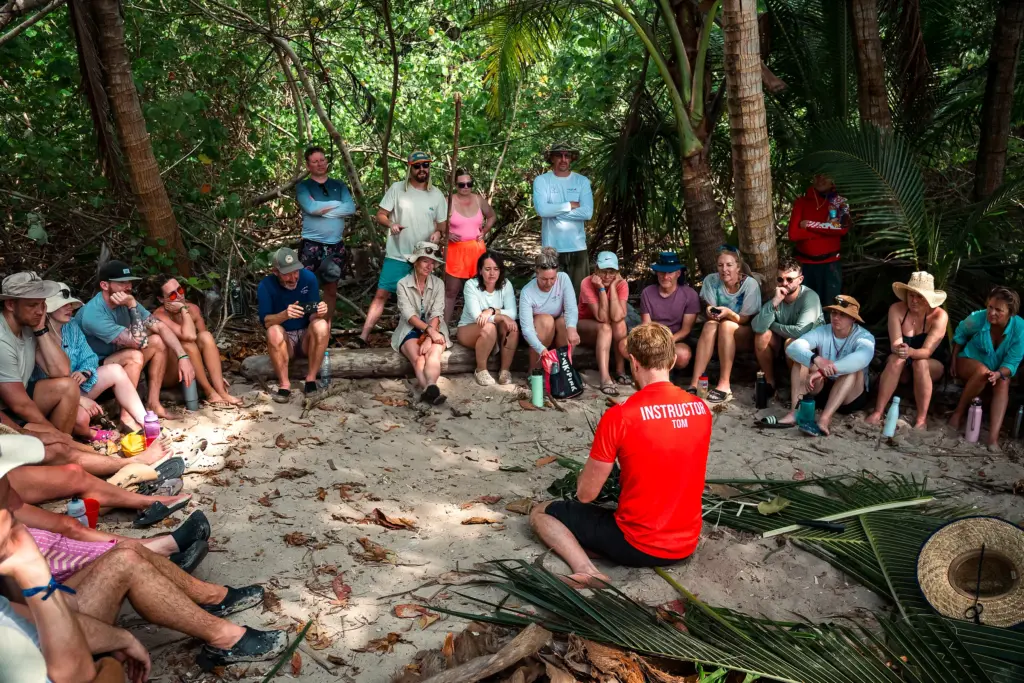 Desert Island Survival instructor briefing a seated group under the trees before a skills session