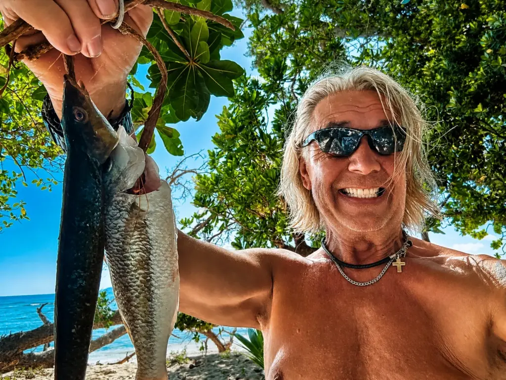 Man with sunglasses and two fish on a tropical beach