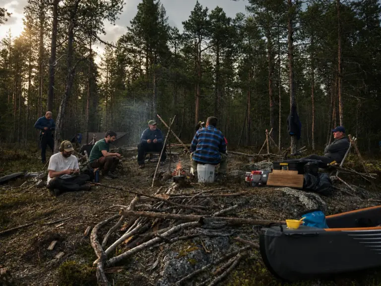 Group of people camping in a forest with a campfire